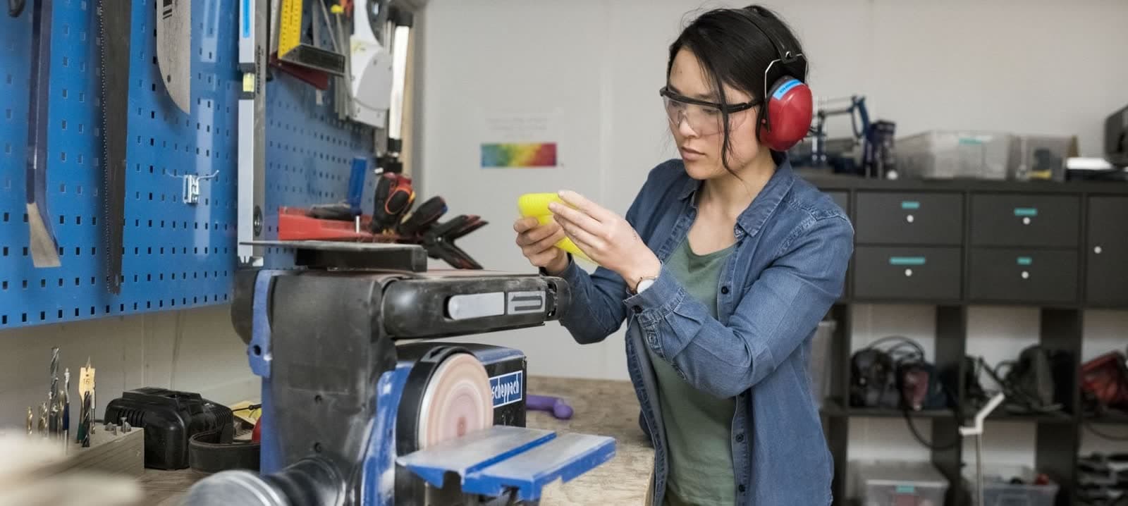 Marianne med hørselvern ved arbeidsbenken i makerspacet